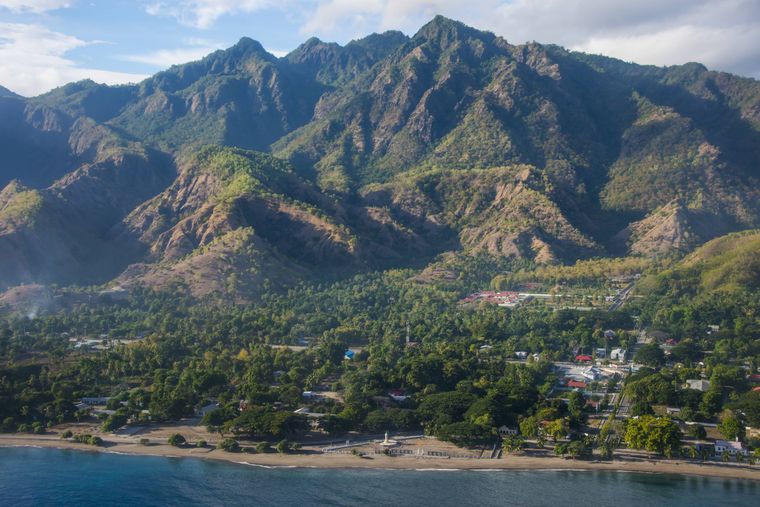 Pemandangan pantai Timor Timur dengan latar belakang pantai dan pegunungan.