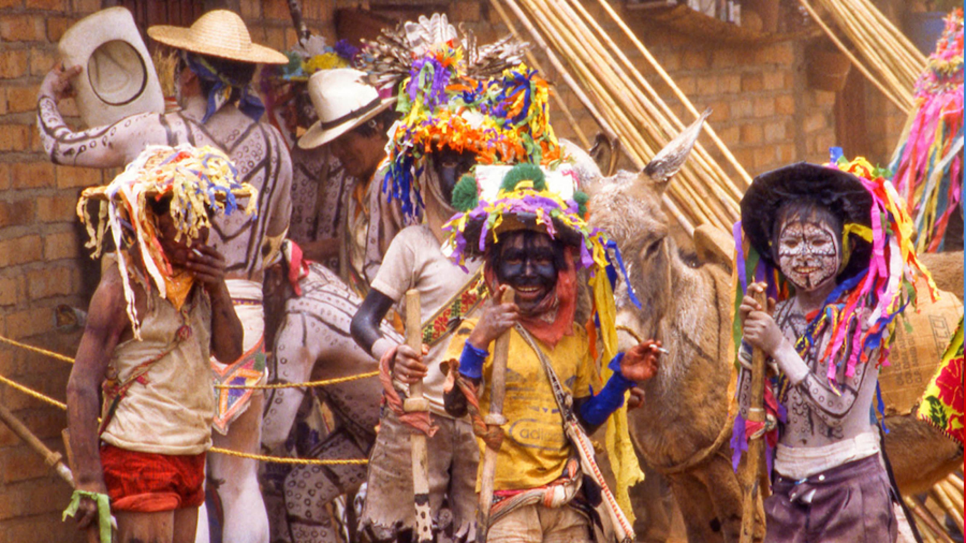 Pemandangan jalanan Mexico City dengan orang-orang yang bersuka ria mengenakan kostum warna-warni.  Antara keledai dan penjual sombrero